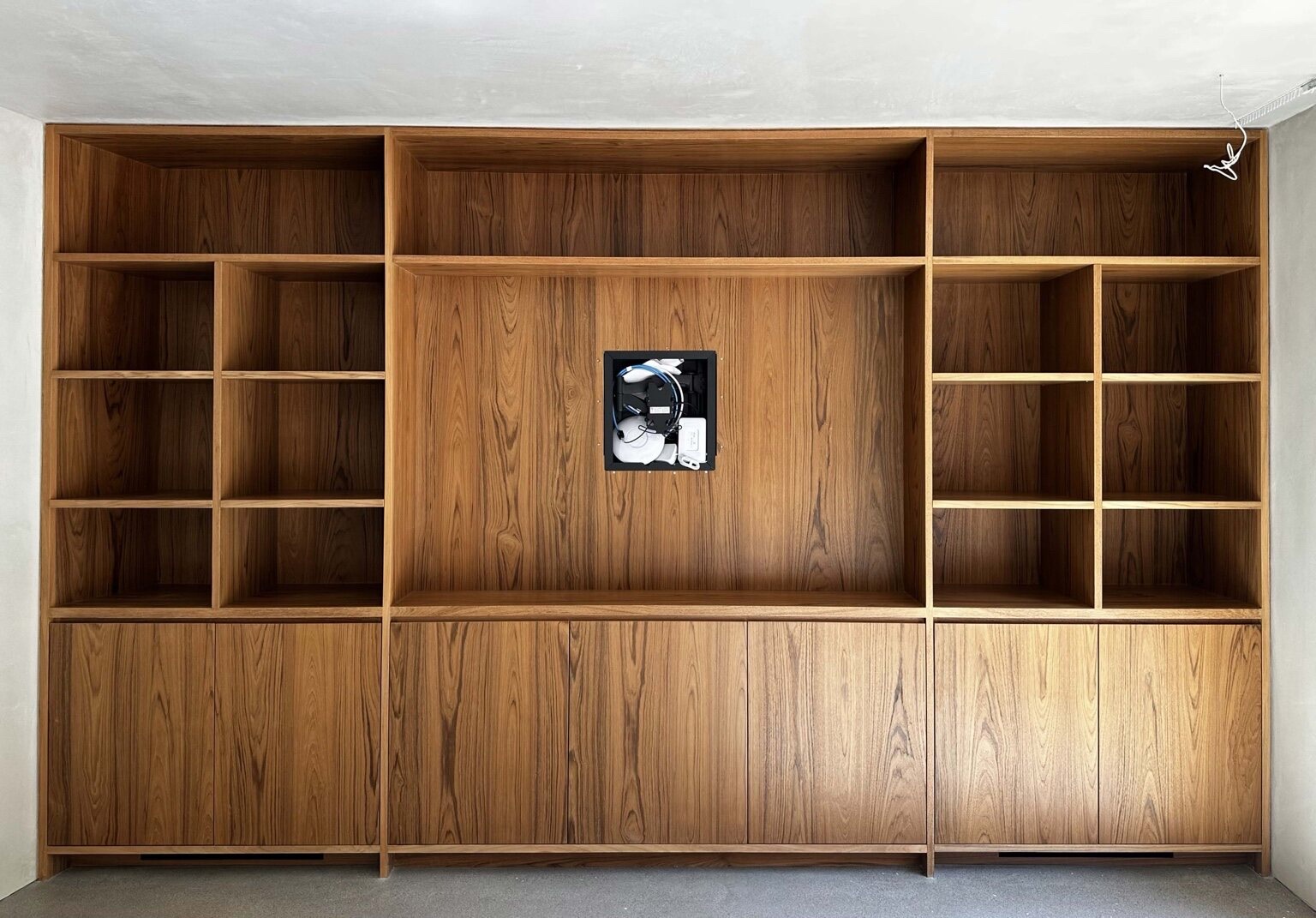Full-height teak built-in wall unit with open shelving, cubbies, and lower cabinet doors