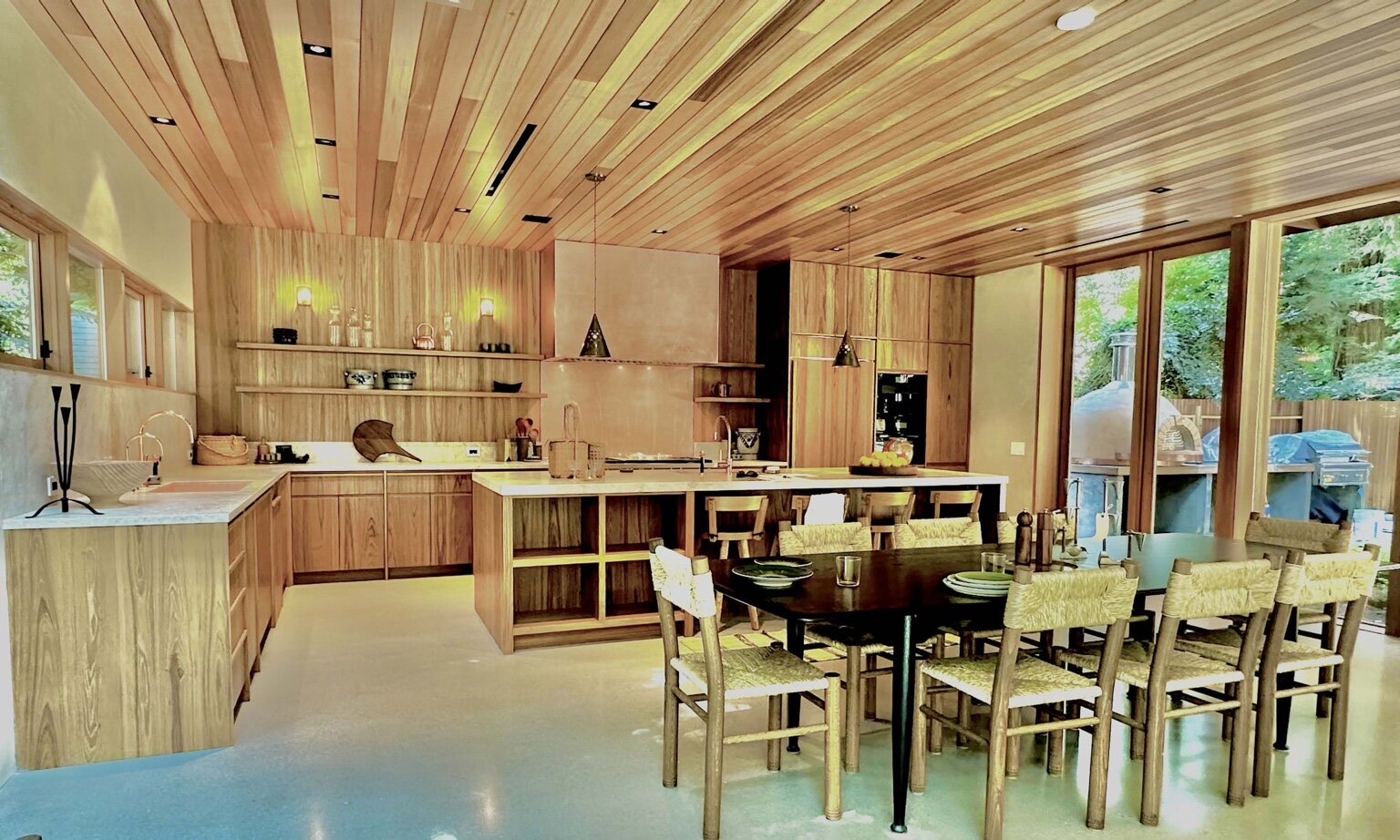 Custom wood kitchen with slatted cedar ceiling, walnut cabinetry, island, and marble counters